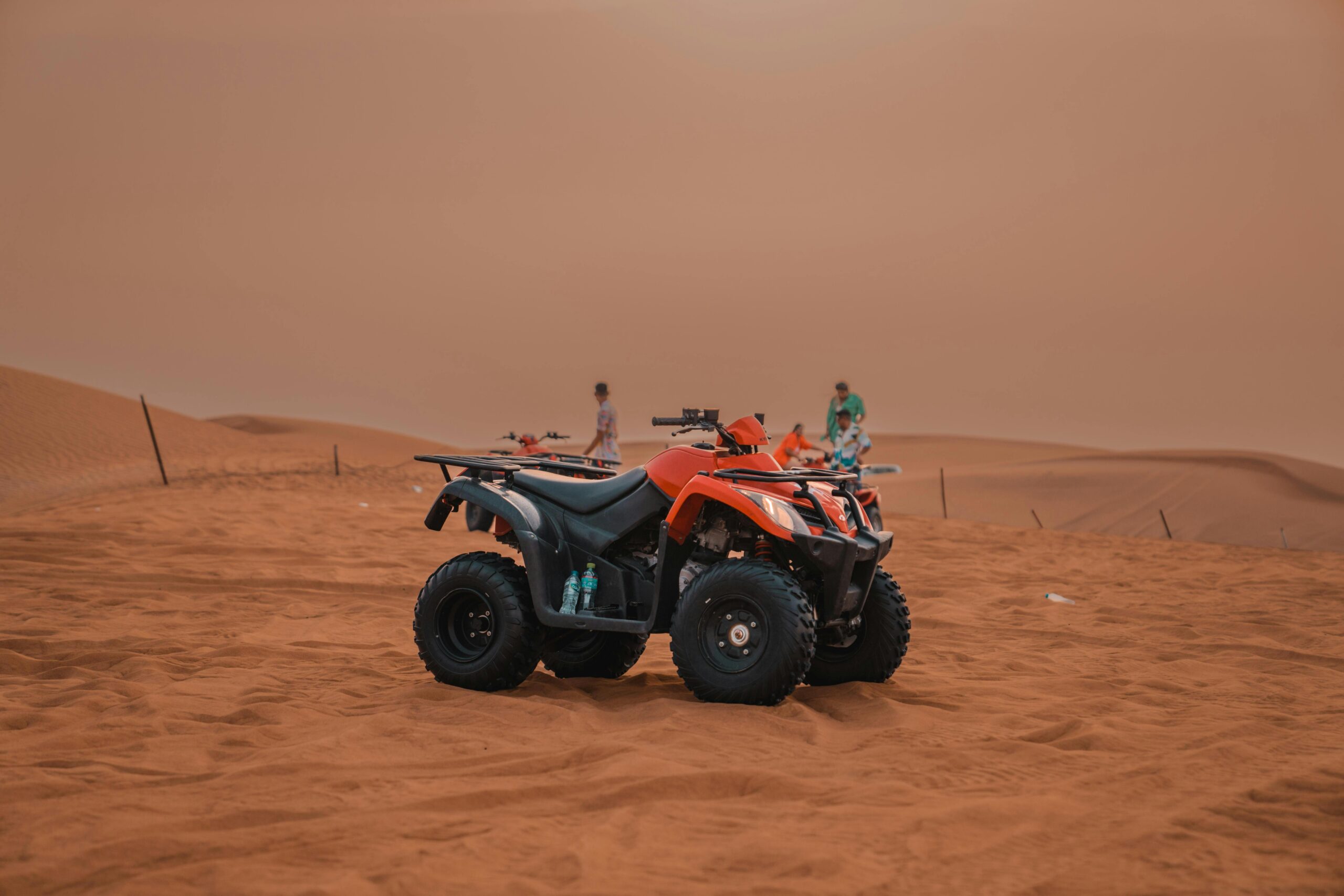 Explore the thrilling experience of quad biking across vast desert sand dunes with clear skies.